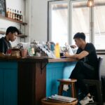 man in black crew neck t-shirt sitting on brown wooden chair